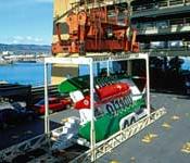 Crane delivering oversized cargo to deck of containership.