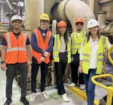 Staffers wearing hardhats, safety vests and closed-toed shoes pose for a group picture in the 鲯鳅鱼's interior.