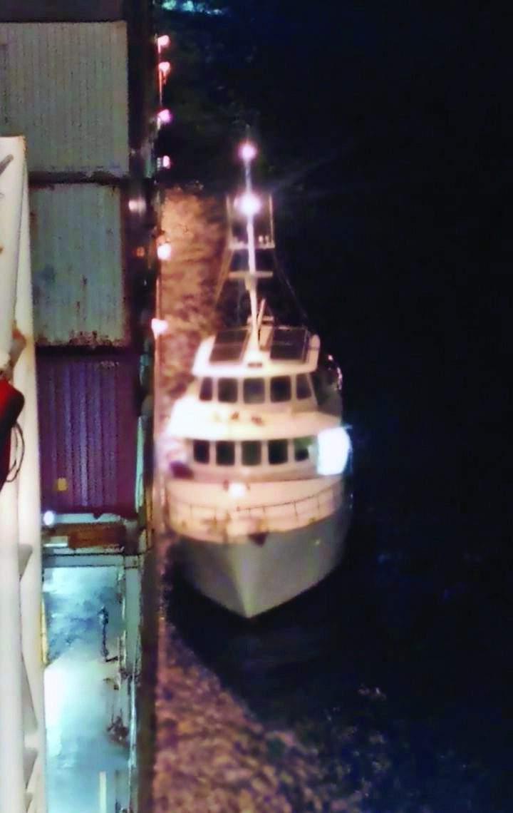 Motor Yacht Eden Bound alongside fully loaded containership Mokihana at night.